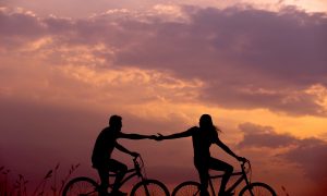 Dvaja zaľúbenci na bicykloch pri západe slnka