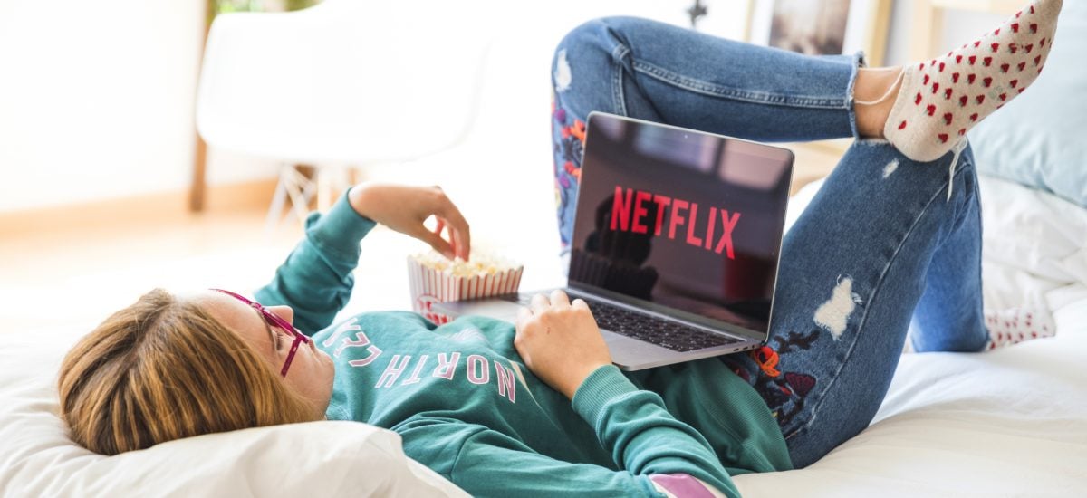 dievča pozerá Netflix na posteli