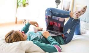 dievča pozerá Netflix na posteli