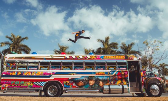 Freerunner predvádzajúci trik nad farebným autobusom v Paname
