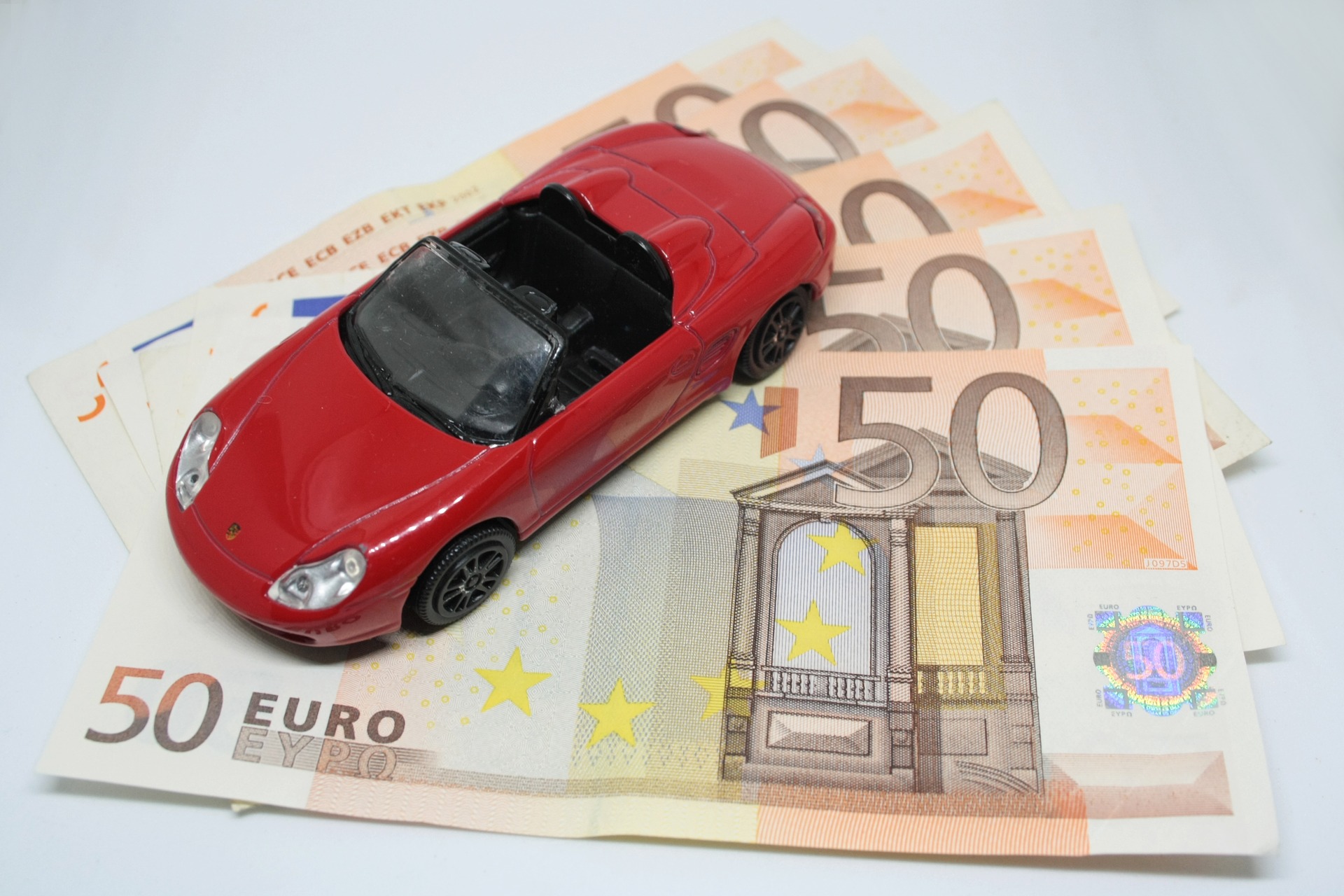 hračkárske červené autíčko na 50 eurových bankovkách