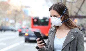 Žena s respirátorom a mobilom.