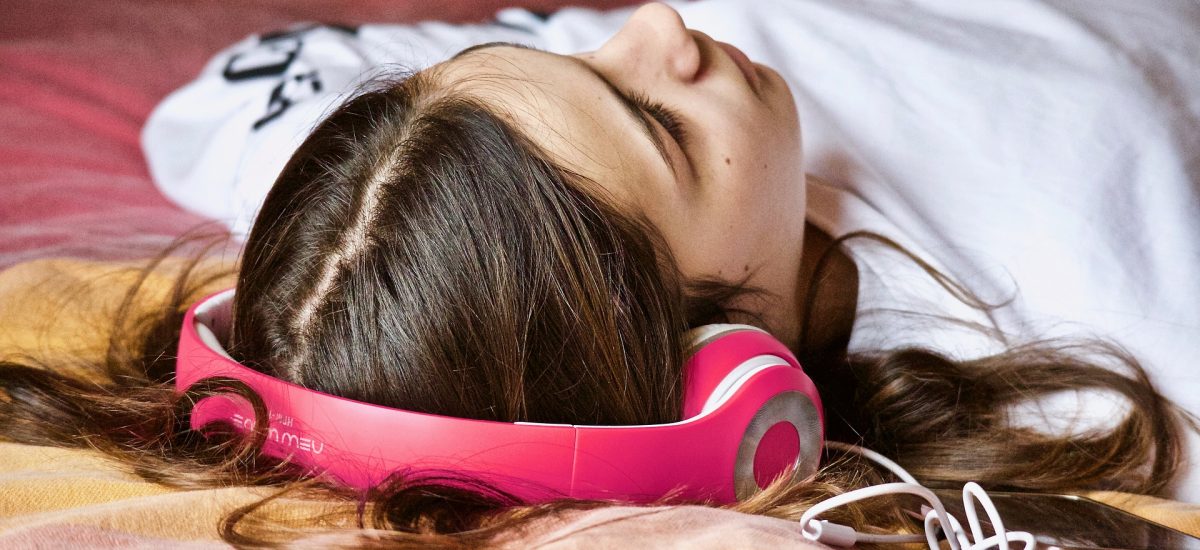 Dievča leží, relaxuje a počúva hudbu v slúchadlách.