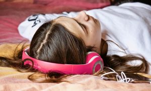 Dievča leží, relaxuje a počúva hudbu v slúchadlách.