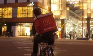 Poslíček z McDonald's Delivery na bicykli.