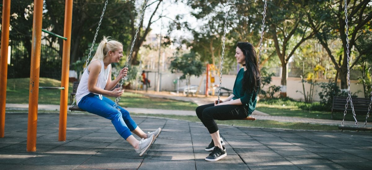 dve kamarátky sa rozprávajú a hojdajú na hojdačkách v parku