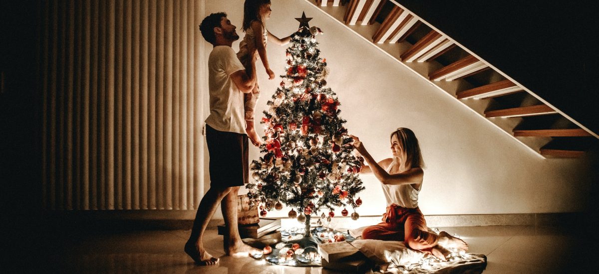 žena, muž a dieťa zdobia vianočný stromček - zelené Vianoce