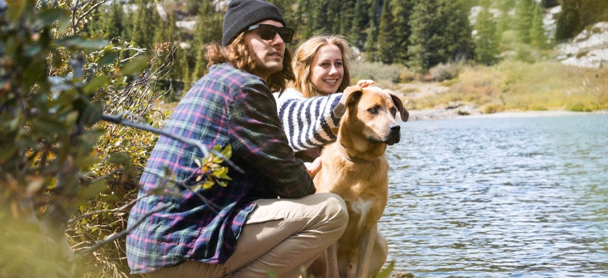 Mladý muž a žena na prechádzke so psom pri rieke