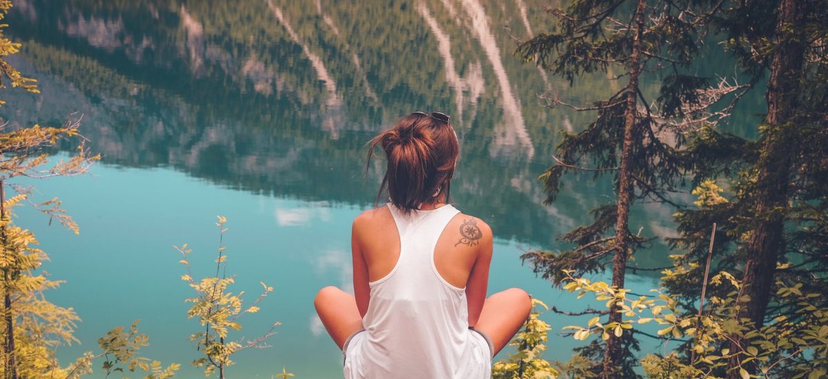 Mladá žena sedí na skale s výhľadom na jazero