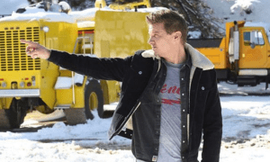 herec Jeremy Renner a snežný pluh v pozadí