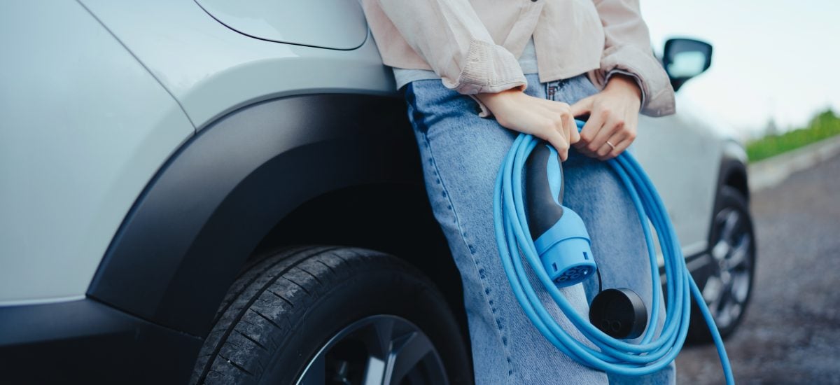 Žena drží nabíjací kábel z elektromobilu