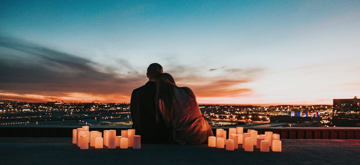 Dvojica sediaca na streche pri sviečkach pozoruje mesto